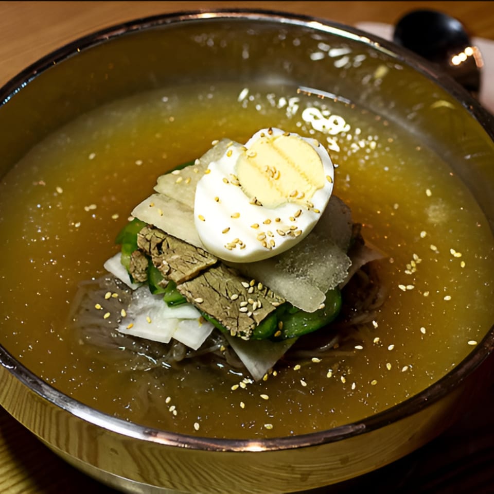 Garionban's Korean cold noodles (naengmyeon) with beef, radish, cucumber, and a boiled egg, sprinkled with sesame seeds.