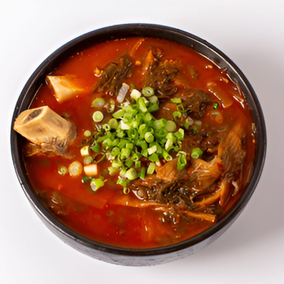A close-up of Garionban's Korean Gamjatang, a spicy pork bone soup with green onions.