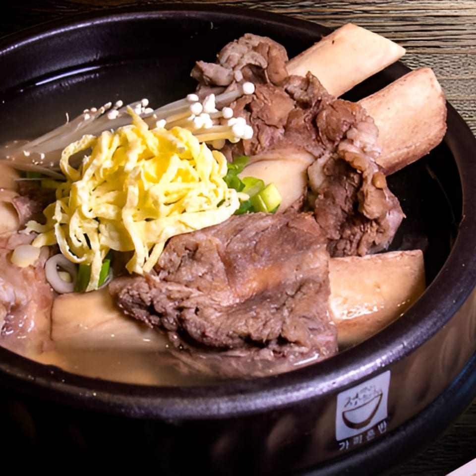 Korean Galbitang, a beef short rib soup, with egg garnish and mushrooms in a black bowl.